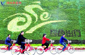 市民騎公共自行車路過(guò)市人民廣場(chǎng)一處花壇。記者 張馳